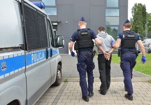 Policjanci prowadzą zatrzymanego