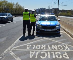 Policjanci przed radiowozem kontrolują ruch