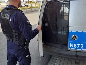 policjant zamyka drzwi policyjnego radiowozu