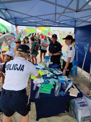 Policyjny namiot na plaży oraz odwiedzający plażowicze