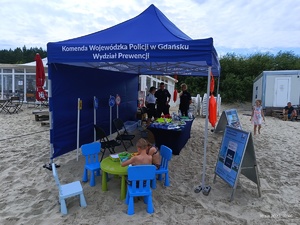 Policyjny namiot na plaży oraz odwiedzający plażowicze