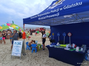 Policyjny namiot na plaży oraz odwiedzający plażowicze