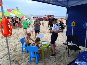 Policyjny namiot na plaży oraz odwiedzający plażowicze