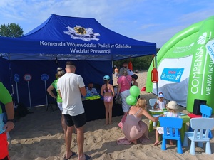 Policyjny namiot na plaży oraz odwiedzający plażowicze