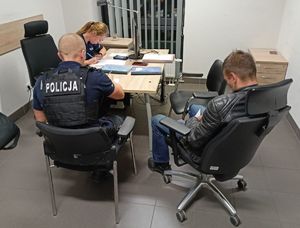 policjant podczas wykonywania dokumentacji z zatrzymanym motocyklistą