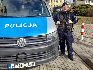 policjant stoi przy radiowozie