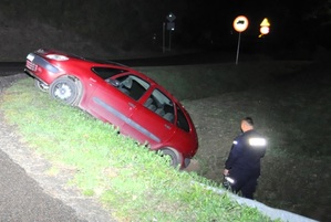 na zdjęciu auto w rowie obok niego stoi umundurowany policjant