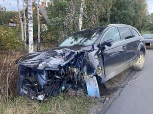 rozbity samochód, który wjechał do rowu obok niego na jezdni stoi oznakowany policyjny radiowóz