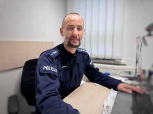 Policjant patrzy w obiektyw siedzi za biurkiem