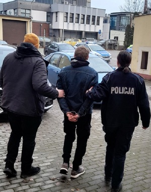 Policjanci prowadzą zatrzymanego
