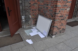 zniszczona tablica leżąca na chodniku