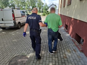 policjanci prowadzą do radiowozu zatrzymanych poszukiwanych mężczyzn