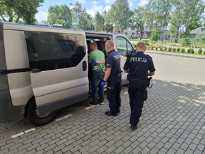 policjanci prowadzą do radiowozu zatrzymanych poszukiwanych mężczyzn