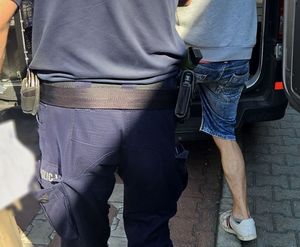 policjant wprowadza zatrzymanego do radiowozu
