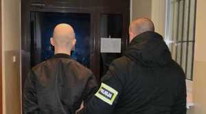 policjant z zatrzymanym i napisy na elewacji