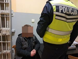 policjant stoi przed zatrzymanym, który siedzi na krześle