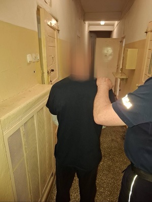 policjant prowadzi zatrzymanego