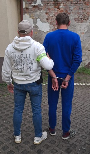 policjant prowadzi zatrzymanego