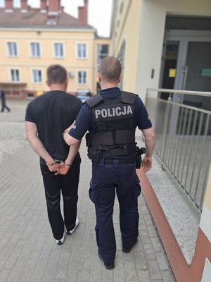policjant prowadzi zatrzymanego