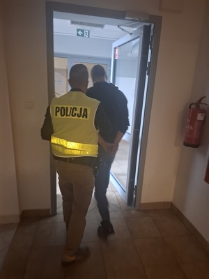 policjant prowadzi zatrzymanego