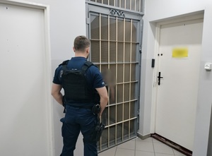 policjant przy celi zatrzymanego