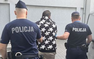 policjanci prowadzą do radiowozu poszukiwanych