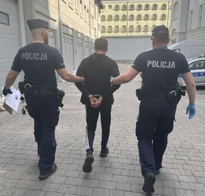 policjanci prowadzą do radiowozu poszukiwanych