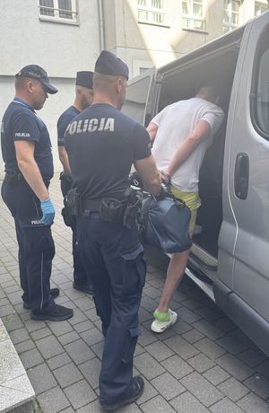 policjanci prowadzą do radiowozu poszukiwanych