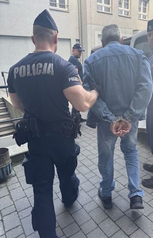 policjanci prowadzą do radiowozu poszukiwanych