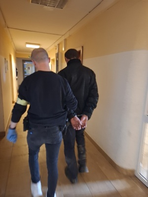 Zdjęcie przedstawia policjanta z zatrzymanym