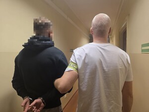 Zdjęcie przedstawia zatrzymanego z policjantem.