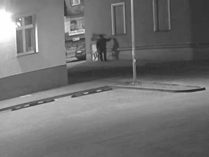 Zdjęcie przedstawia mężczyznę, umieszczającego napis na elewacji budynku.