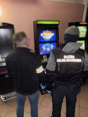 Zdjęcie przedstawia policjantów oraz funkcjonariuszy KAS w punkcie nielegalnych gier hazardowych.