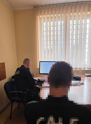 Zdjęcie przedstawia policjantów z zatrzymanym oraz ich pojazdy.