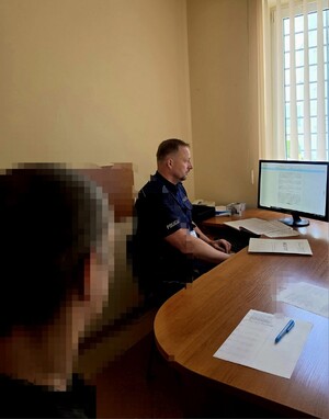 Zdjęcie przedstawia policjantów z zatrzymanym oraz ich pojazdy.